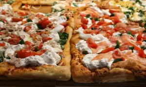 Pyszna pizza na cienkim cieście z burratą, pomidorkami i łososiem.