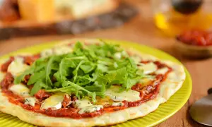 Pyszna pizza z patelni z rukolą i serem pleśniowym, podana na zielonym talerzu.