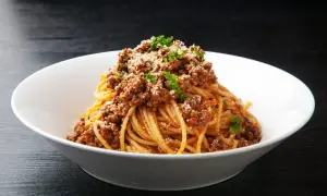 Pyszne spaghetti z bogatym sosem bolognese, posypane parmezanem i natką pietruszki. Idealne danie z makaronem z mięsem mielonym.