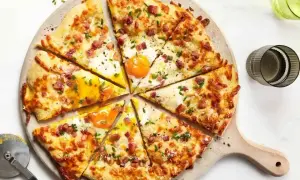 Pyszna pizza z jajkiem i boczkiem, posypana szczypiorkiem. Idealne dodatki do pizzy, które zachwycą każdego smakosza.