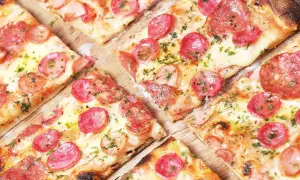 Kawałki pizzy z kiełbasą i serem, idealne na szybki przepis na ciasto do pizzy.