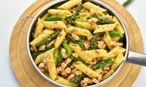 Penne z kurczakiem i szparagami, posypane papryką. Pyszne danie na obiad.