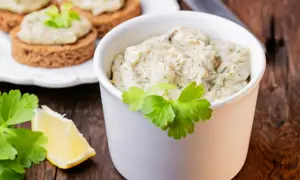 Pyszna pasta z makreli i jajek, podana w białej miseczce, z dodatkiem cytryny i natki pietruszki. Idealna na kanapki.