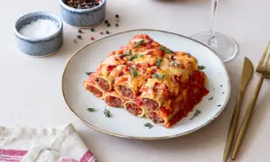 Pyszne cannelloni z mięsem mielonym, zapieczone pod sosem pomidorowym i serem, ozdobione świeżym tymiankiem.
