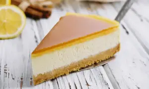 Pyszny sernik z mascarpone na kruchym spodzie, z delikatną galaretką na wierzchu. Obok cytryna i laski cynamonu.