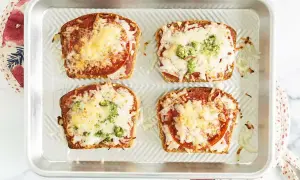 Cztery zapiekane kromki chleba tostowego z sosem, serem, salami i brokułami. Szybka pizza z chleba tostowego gotowa do podania.