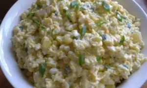 Szybka sałatka z ryżem i jajkiem, z dodatkiem szczypiorku, w białej misce. Idealna na szybki lunch.