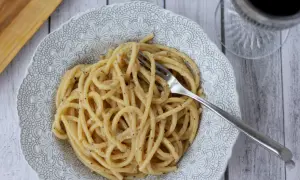 Porcja kremowego cacio e pepe z widelcem w talerzu, gotowa do zjedzenia.