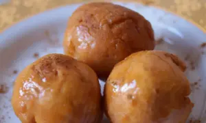 Trzy złociste pączki, lekko posypane cynamonem, wyglądają apetycznie. Idealne na tłusty czwartek, zgodnie z tym przepisem na pączki.
