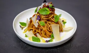 Pyszne spaghetti alla norma z sosem pomidorowym, bakłażanem, bazylią i płatkami parmezanu.