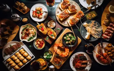 Tapas co to? Kolorowy stół pełen przekąsek: krewetki, pieczywo, ser, oliwki i inne smakołyki. Idealne na spotkanie.