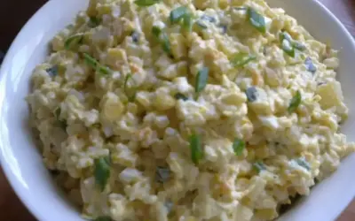 Szybka sałatka z ryżem i jajkiem, z dodatkiem szczypiorku, w białej misce. Idealna na szybki lunch.