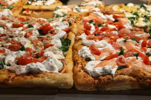 Pyszna pizza na cienkim cieście z burratą, pomidorkami i łososiem.