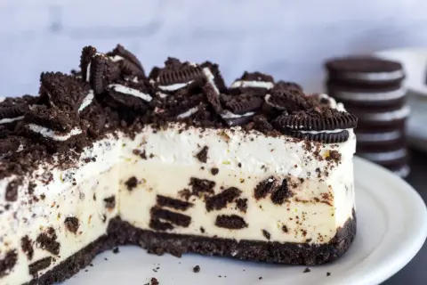 Pyszny sernik oreo na zimno, udekorowany pokruszonymi ciasteczkami i całymi oreo. Idealny deser dla miłośników czekolady.