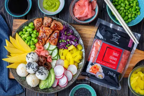 Kolorowy bowl z kawałkami łososia w sosie, ryżowymi kulkami, mango, awokado, ogórkiem, rzodkiewką, edamame i marynowanym imbirem.
