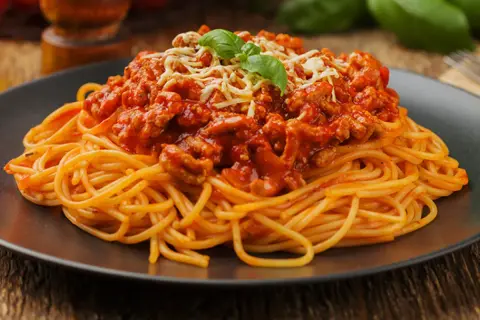 Pyszne spaghetti bolognese z mielonym mięsem, polane sosem pomidorowym i posypane serem. Idealne pytanie: jakie mięso do spaghetti?