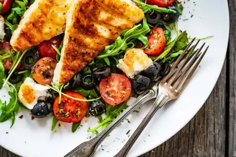 Pyszna sałatka na grilla z grillowanym serem halloumi, pomidorkami i oliwkami. Idealna na letnie wieczory.