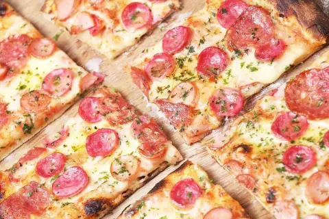 Kawałki pizzy z kiełbasą i serem, idealne na szybki przepis na ciasto do pizzy.