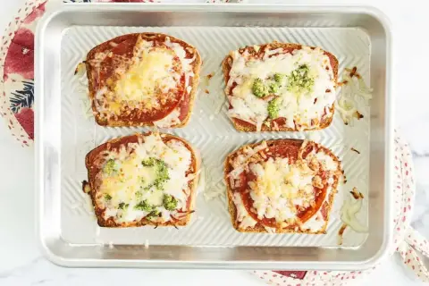 Cztery zapiekane kromki chleba tostowego z sosem, serem, salami i brokułami. Szybka pizza z chleba tostowego gotowa do podania.