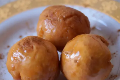 Trzy złociste pączki, lekko posypane cynamonem, wyglądają apetycznie. Idealne na tłusty czwartek, zgodnie z tym przepisem na pączki.
