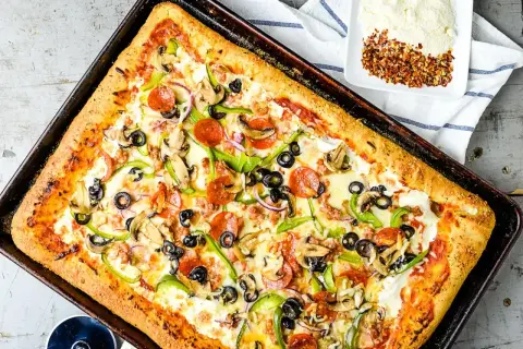 Pyszna pizza domowa na blachę z pieczarkami, papryką, oliwkami i pepperoni. Idealny przepis na szybki obiad.