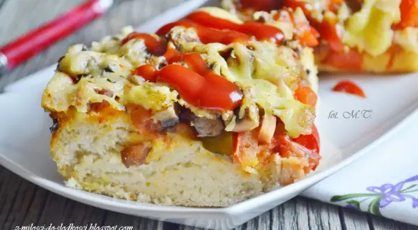 Pyszna pizza na grubym cieście z serem, pieczarkami i pomidorami, polana ketchupem.