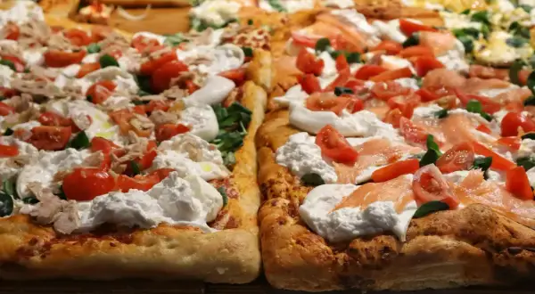Pyszna pizza na cienkim cieście z burratą, pomidorkami i łososiem.