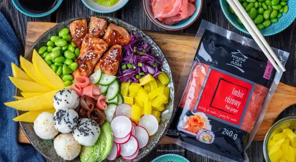 Kolorowy bowl z kawałkami łososia w sosie, ryżowymi kulkami, mango, awokado, ogórkiem, rzodkiewką, edamame i marynowanym imbirem.