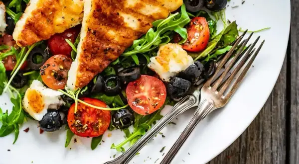 Pyszna sałatka na grilla z grillowanym serem halloumi, pomidorkami i oliwkami. Idealna na letnie wieczory.