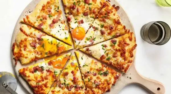 Pyszna pizza z jajkiem i boczkiem, posypana szczypiorkiem. Idealne dodatki do pizzy, które zachwycą każdego smakosza.
