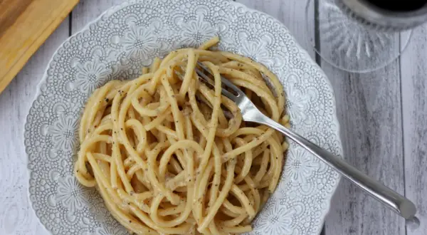 Porcja kremowego cacio e pepe z widelcem w talerzu, gotowa do zjedzenia.