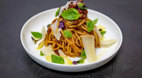 Pyszne spaghetti alla norma z sosem pomidorowym, bakłażanem, bazylią i płatkami parmezanu.
