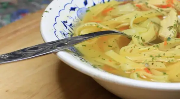 Aromaticzny rosół z makaronem i kawałkami kurczaka, posypany natką. Kiedy solić rosół? Najlepiej pod koniec gotowania, by nie stracił smaku.
