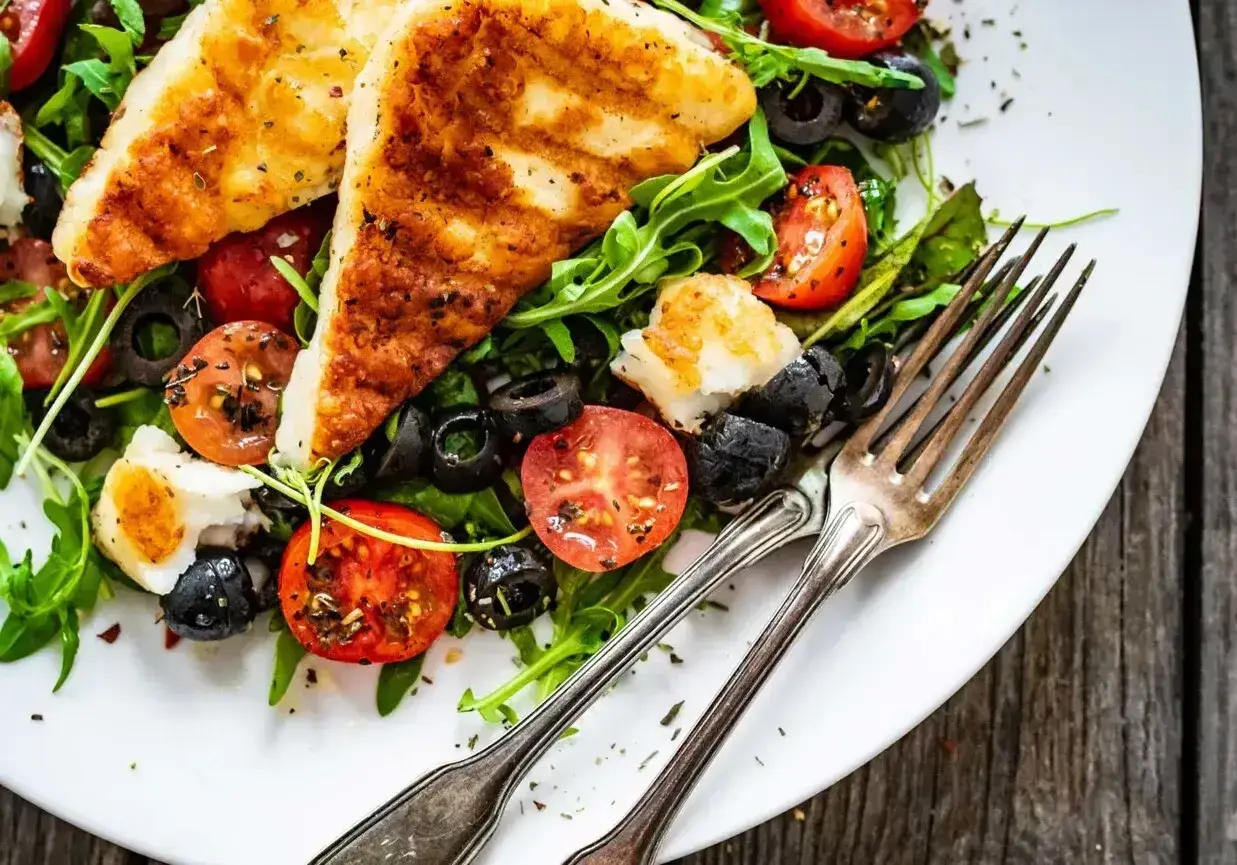 Pyszna sałatka na grilla z grillowanym serem halloumi, pomidorkami i oliwkami. Idealna na letnie wieczory.