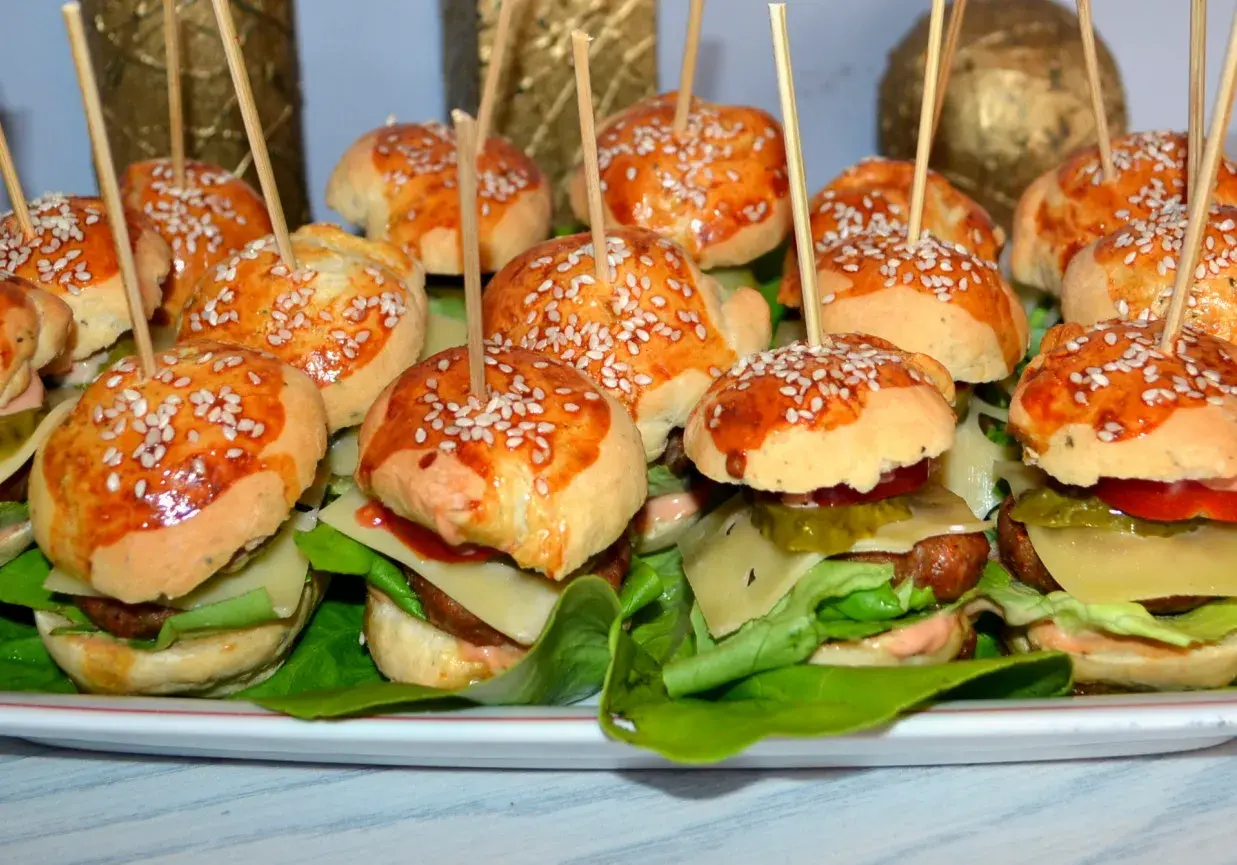 Mini burgery z kurczakiem, idealne na imprezę. Każdy ma sezamową bułeczkę, soczystego kotleta i świeże dodatki.
