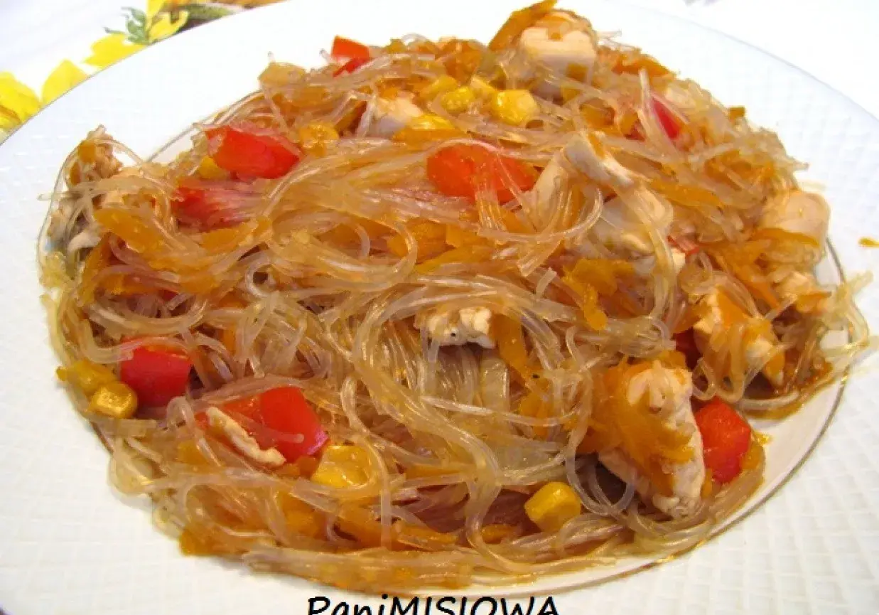 Pyszny makaron sojowy z kurczakiem, papryką i kukurydzą na białym talerzu.