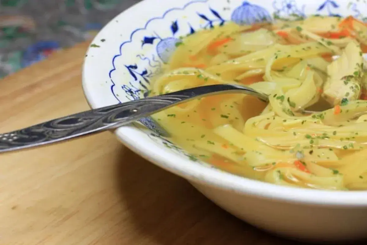 Aromaticzny rosół z makaronem i kawałkami kurczaka, posypany natką. Kiedy solić rosół? Najlepiej pod koniec gotowania, by nie stracił smaku.