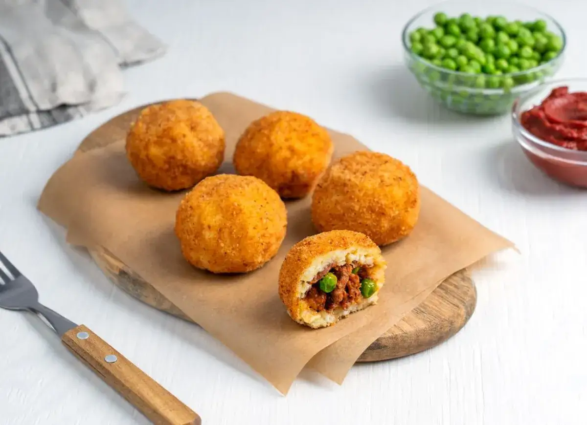 Arancini co to? Złociste kulki ryżowe z mięsem i groszkiem, chrupiące na zewnątrz, miękkie w środku. Pyszna sycylijska przekąska.