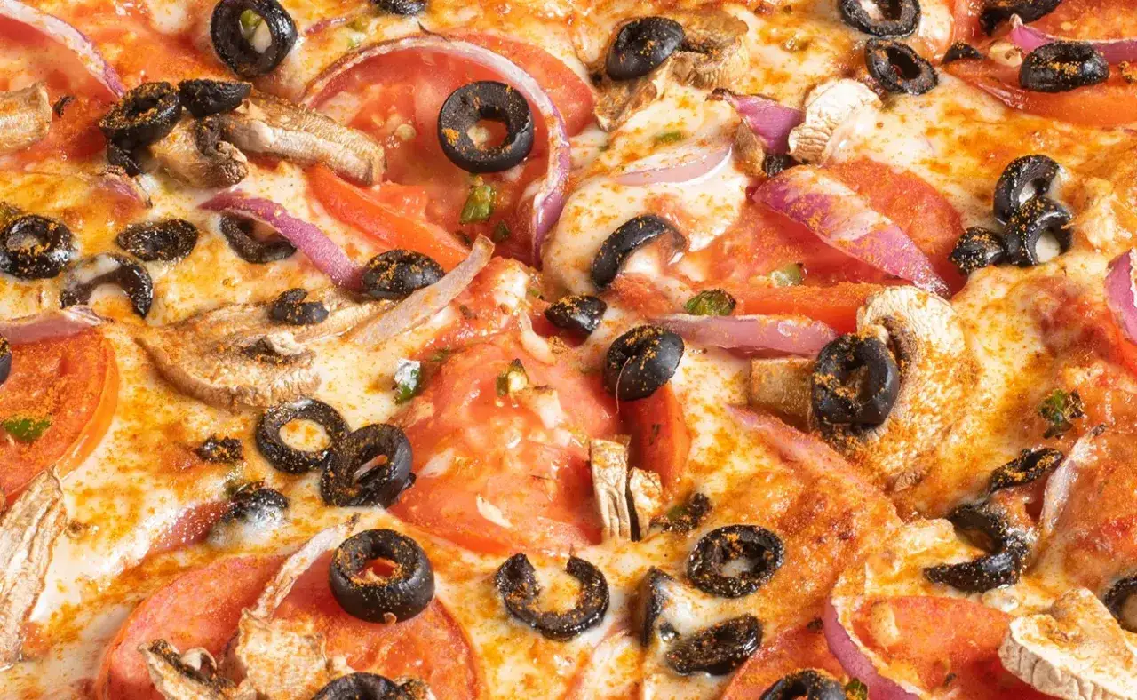 Pyszna pizza z pomidorami, oliwkami, pieczarkami i czerwoną cebulą. Te dodatki do pizzy tworzą idealne połączenie smaków.