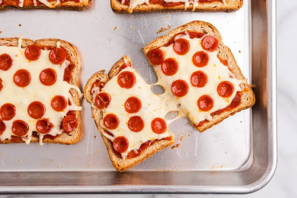 Pyszna pizza z chleba tostowego z roztopionym serem i pepperoni, ułożona na blasze.