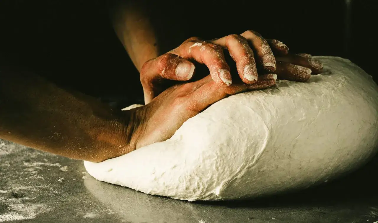 Dłonie wyrabiające ciasto na pizzę neapolitańską. Sekret idealnego przepisu tkwi w cierpliwości i technice.