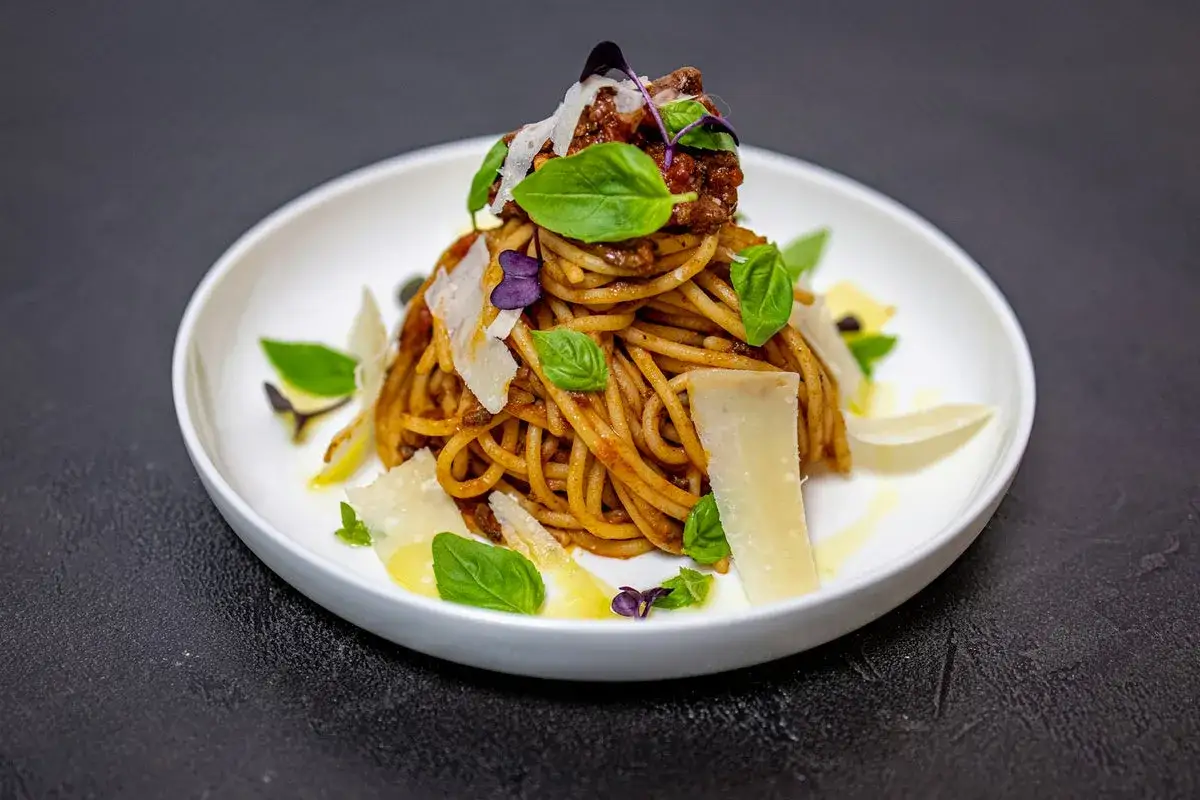 Wykwintne spaghetti alla norma z sosem pomidorowym, bakłażanem, bazylią i płatkami parmezanu.