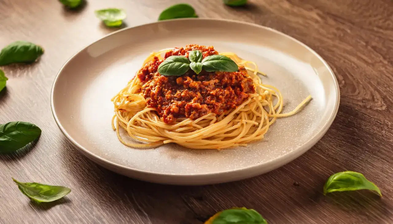 Pyszne spaghetti bolognese, idealne na prosty obiad. Aromatyczny sos mięsny z pomidorami i świeża bazylia na złocistym makaronie.