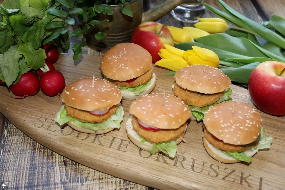 Pięć mini burgery z kurczakiem na desce z rzodkiewkami i jabłkami.