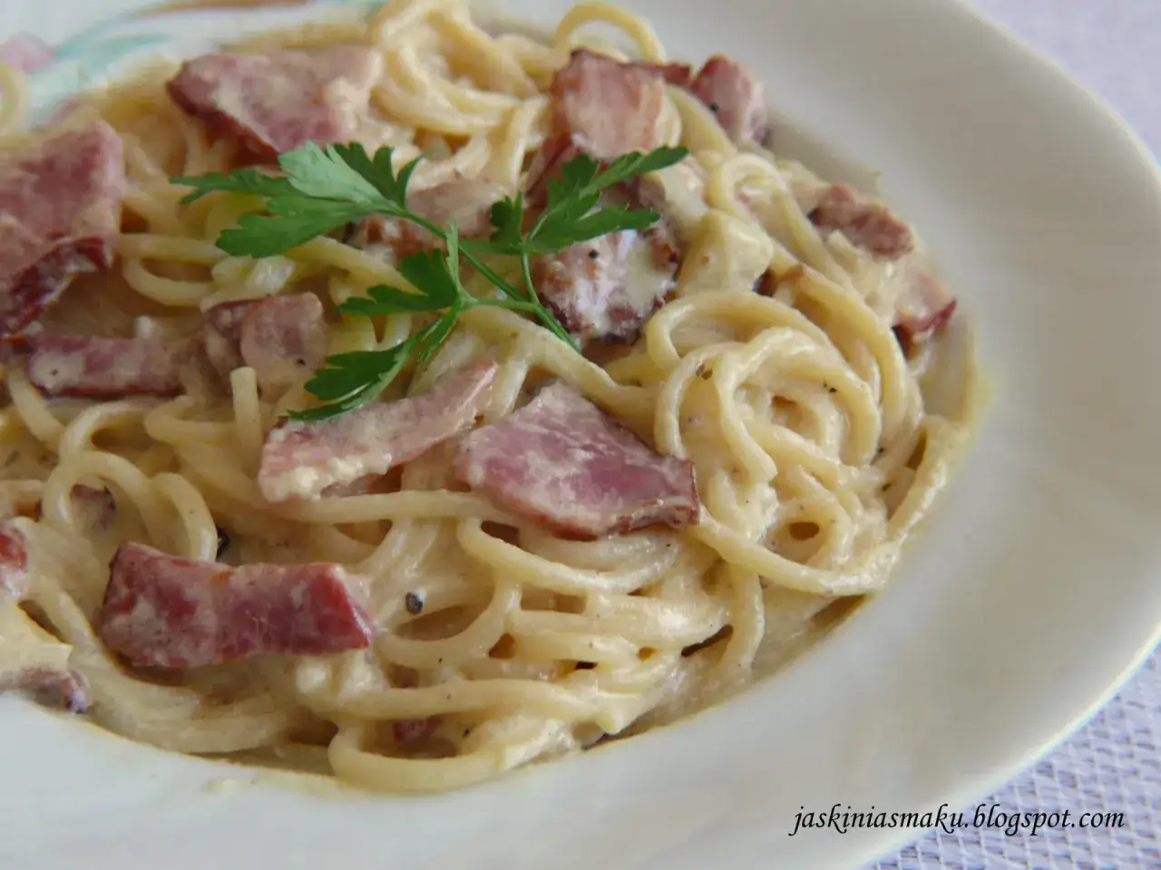 Pyszne spaghetti z boczkiem w kremowym sosie, udekorowane natką pietruszki. Idealne danie dla miłośników makaronu.