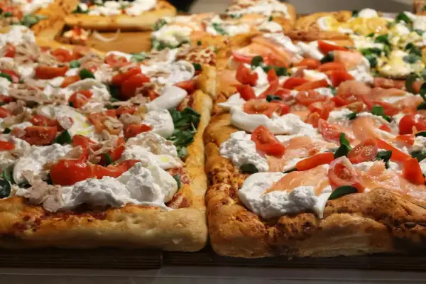 Pyszna pizza na cienkim cieście z burratą, pomidorkami i łososiem.