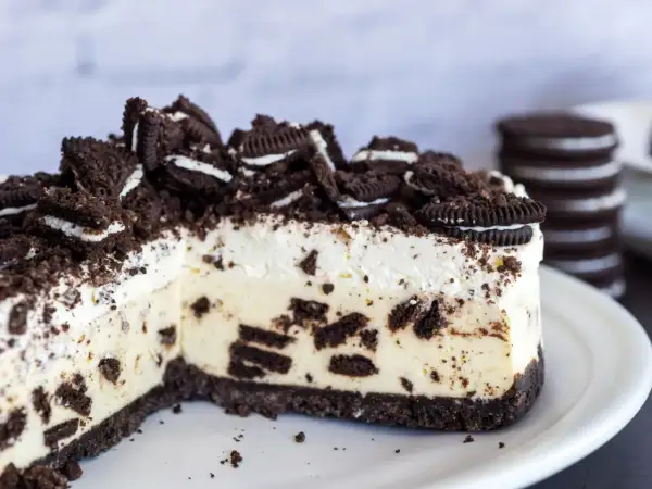 Pyszny sernik oreo na zimno, udekorowany pokruszonymi ciasteczkami i całymi oreo. Idealny deser dla miłośników czekolady.