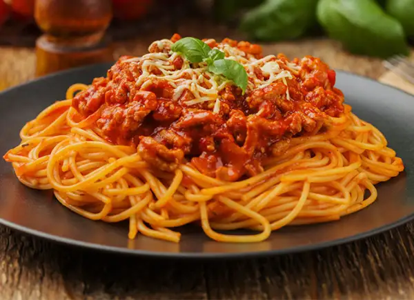 Pyszne spaghetti bolognese z mielonym mięsem, polane sosem pomidorowym i posypane serem. Idealne pytanie: jakie mięso do spaghetti?