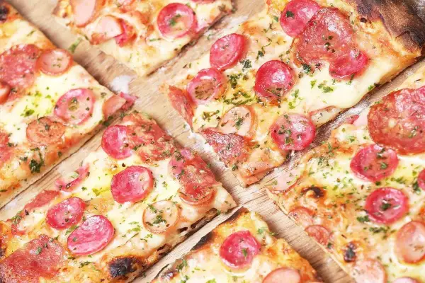 Kawałki pizzy z kiełbasą i serem, idealne na szybki przepis na ciasto do pizzy.