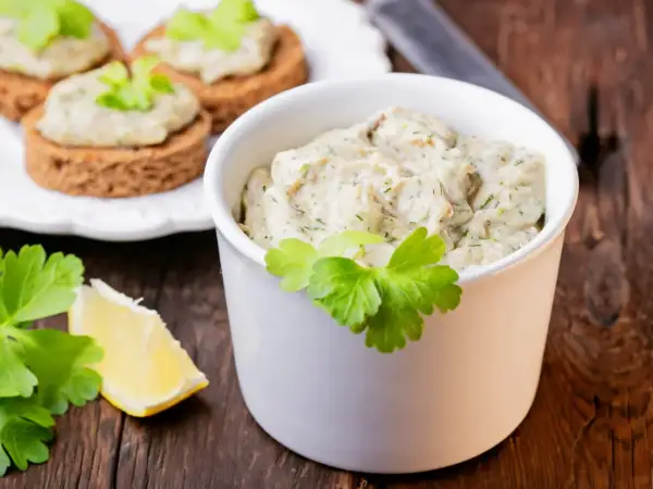 Pyszna pasta z makreli i jajek, podana w białej miseczce, z dodatkiem cytryny i natki pietruszki. Idealna na kanapki.